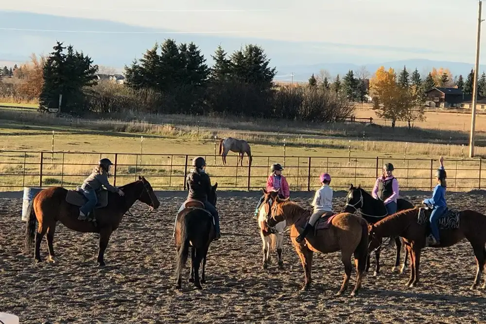 Students taking a horse riding lesson in an arena