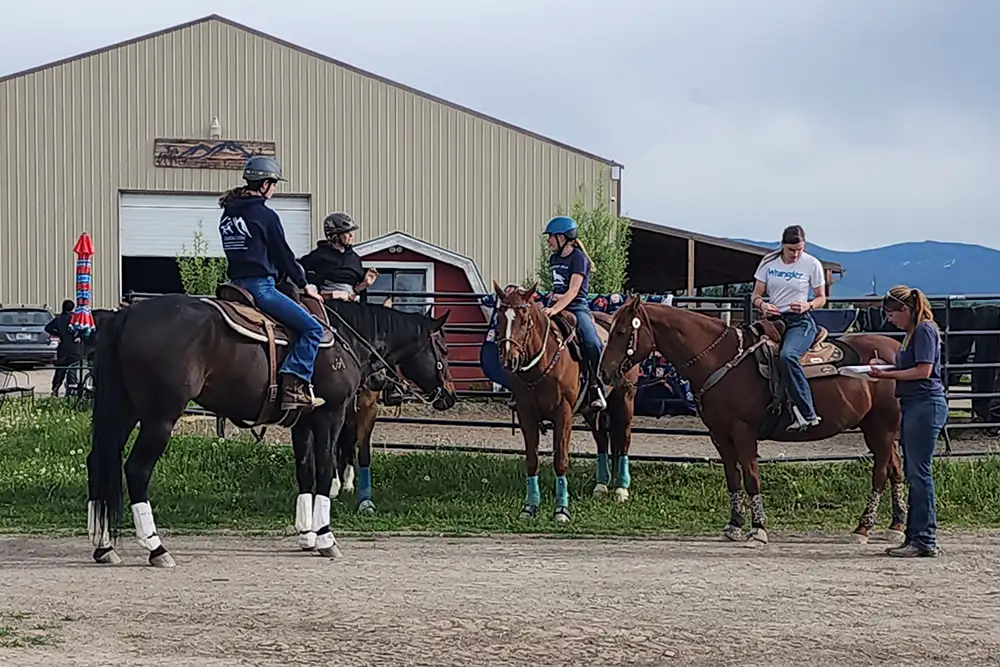 group of girls on horseback talking to instructor