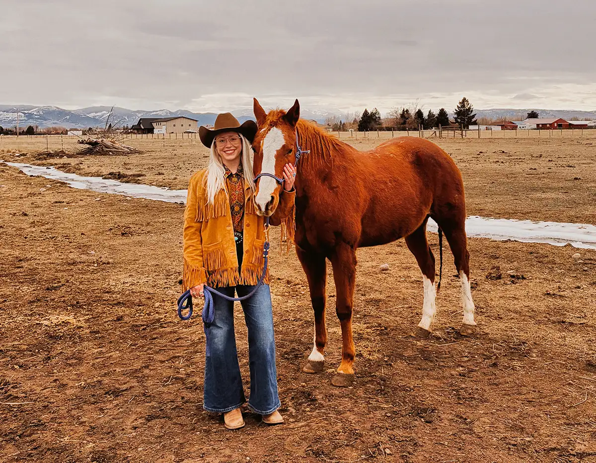 woman with cowboy hat and her horse in a field